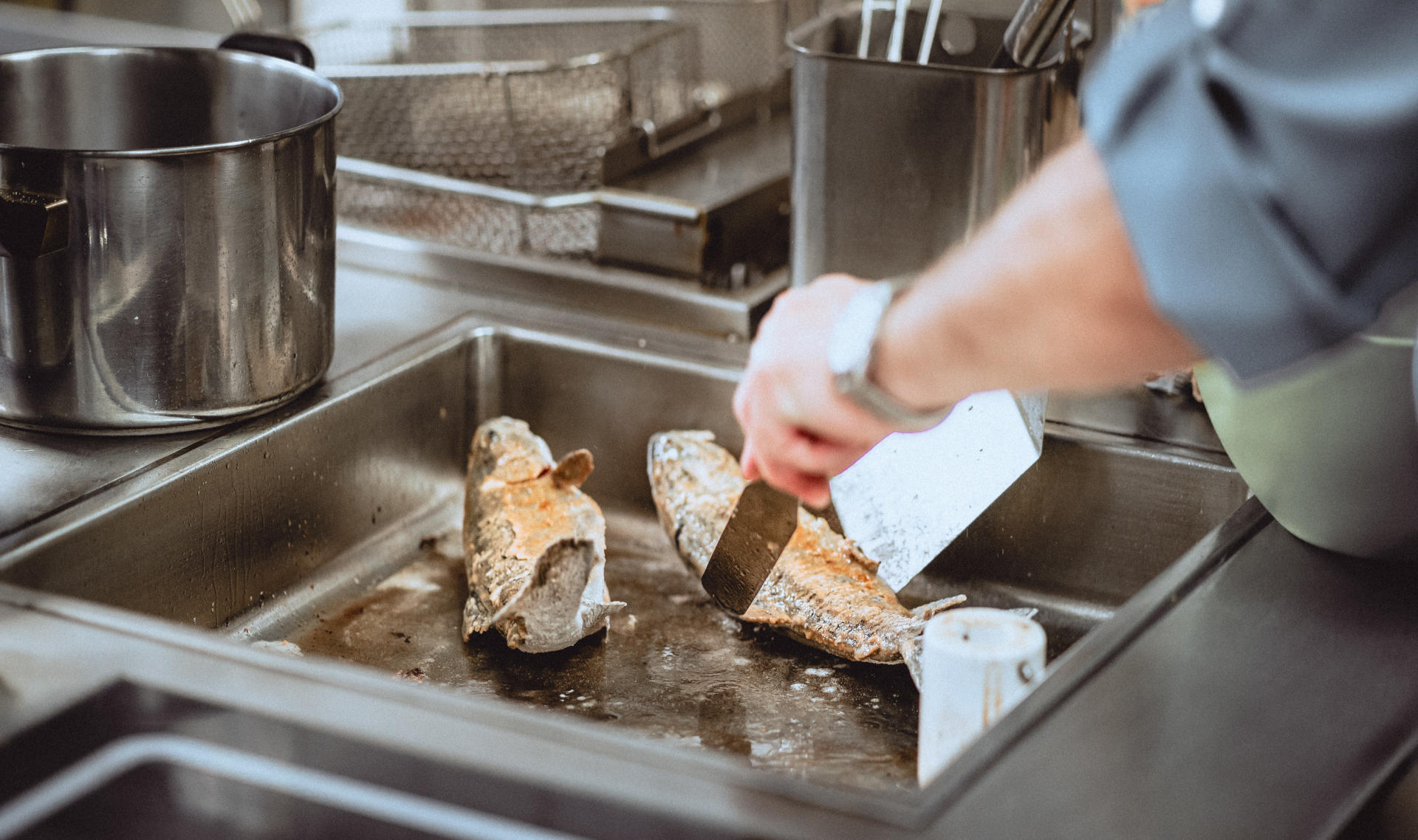 Ein Koch brät Fisch in der Küche des Landgasthauses zur Linde